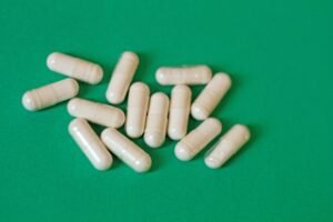 White probiotic-style capsules on a green background